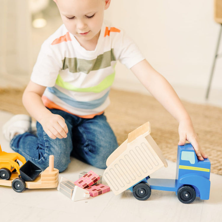 A kid playing with the Melissa & Doug Classic Toy Wooden Dump Truck & Loader with Construction Pieces