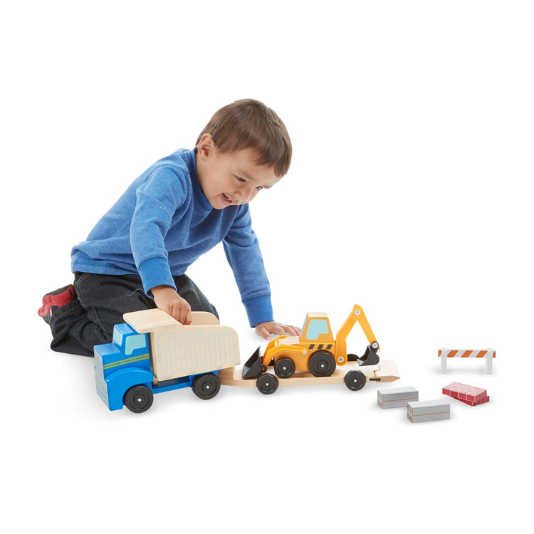 A child on white background with the Melissa & Doug Classic Toy Wooden Dump Truck & Loader with Construction Pieces