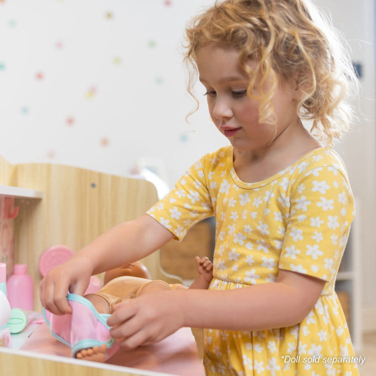A kid playing with the Melissa & Doug Baby Care Center and Accessory Sets