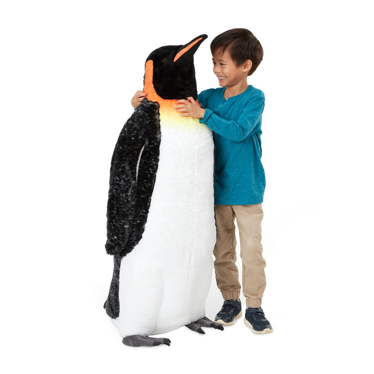 A child on white background with the Melissa & Doug Giant Lifelike Plush Emperor Penguin Standing Stuffed Animal (3.4 Feet Tall)