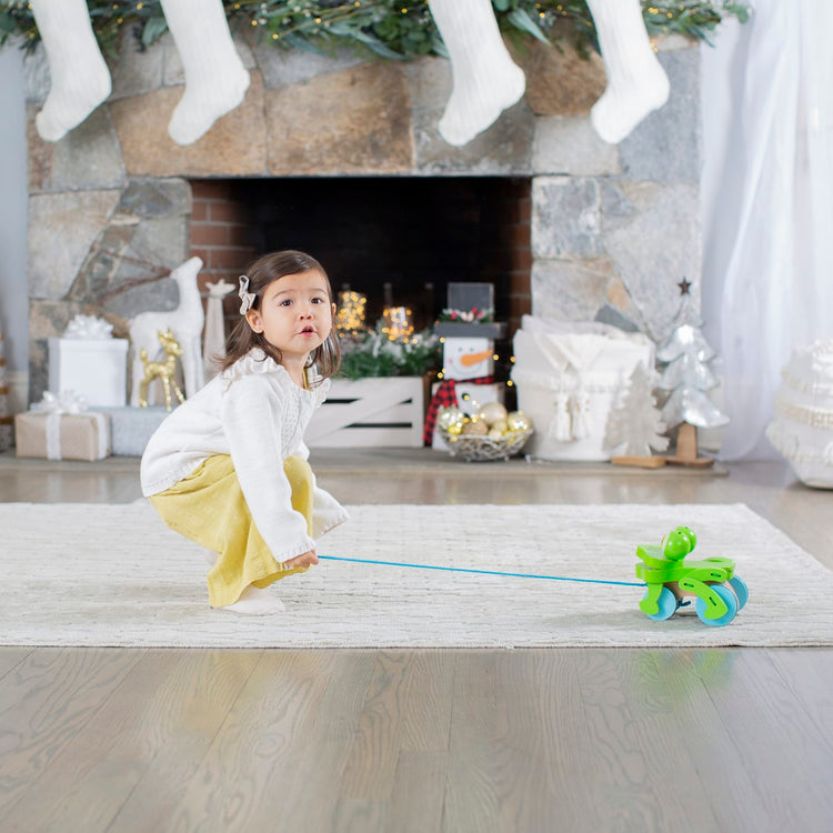A kid playing with the Melissa & Doug First Play Frolicking Frog Wooden Pull Toy