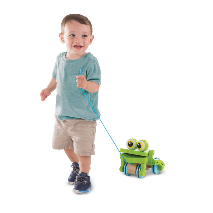 A child on white background with the Melissa & Doug First Play Frolicking Frog Wooden Pull Toy