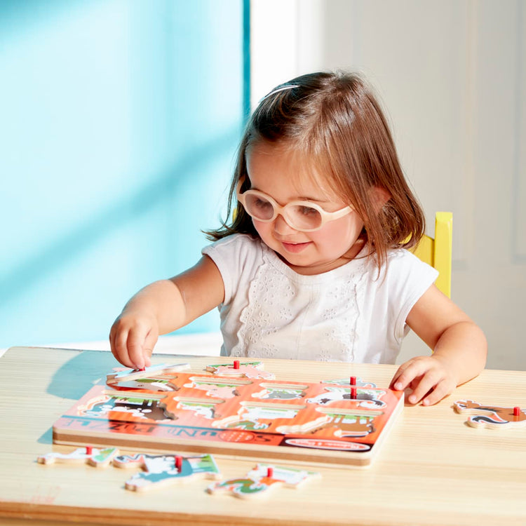 A kid playing with the Melissa & Doug Farm Animals Sound Puzzle - Wooden Peg Puzzle With Sound Effects (8 pcs)