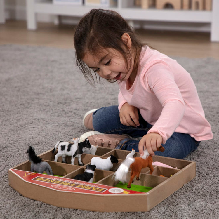 A kid playing with the Melissa & Doug Farm Friends Collectible Toy Animal Figures (10 pcs)