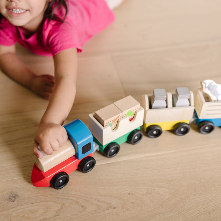 A kid playing with the Melissa & Doug Wooden Farm Train Set - Classic Wooden Toy (3 linking cars)