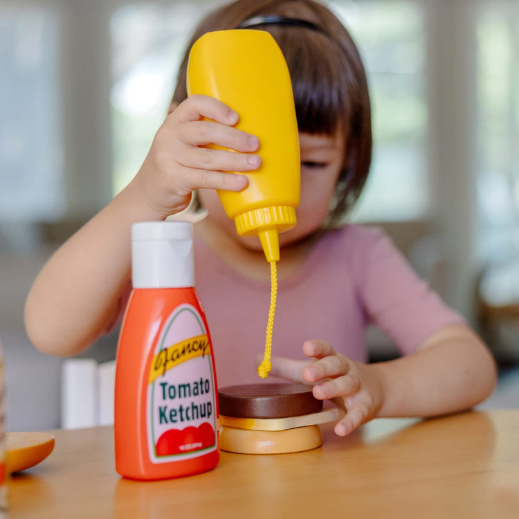 A kid playing with the Melissa & Doug 5-Piece Favorite Condiments Play Food Set