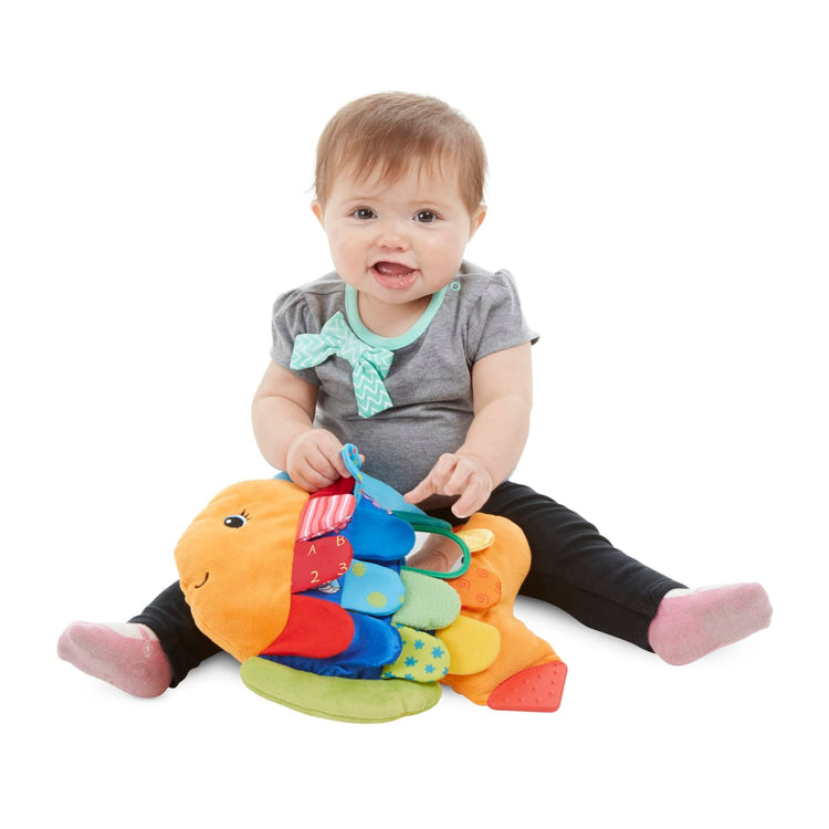 A child on white background with the Melissa & Doug Flip Fish Soft Baby Toy
