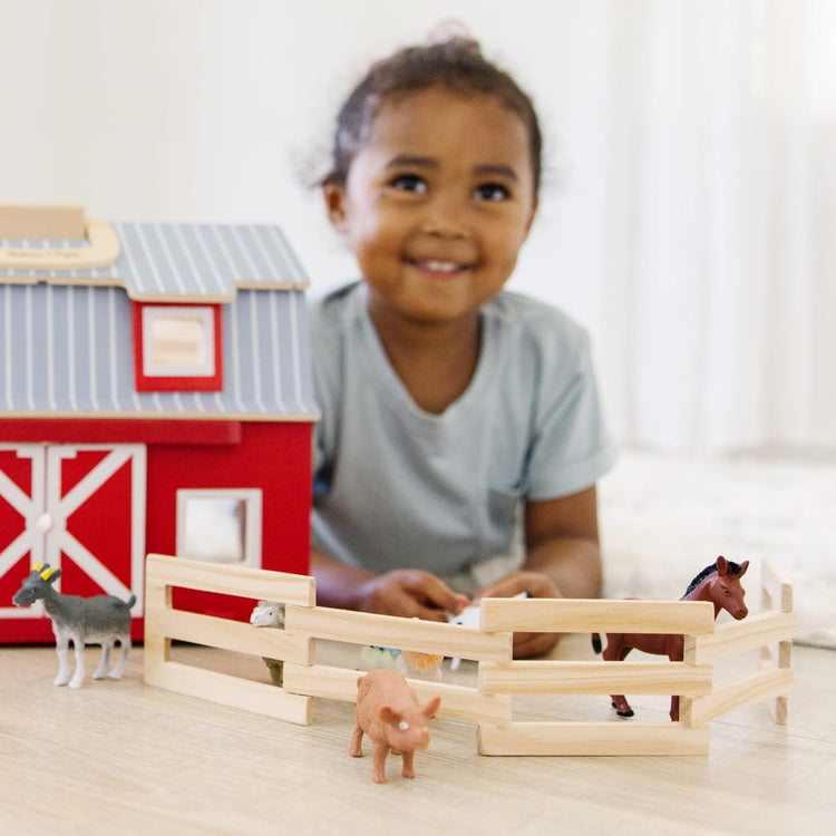 A kid playing with the Melissa & Doug Fold and Go Wooden Barn With 7 Animal Play Figures