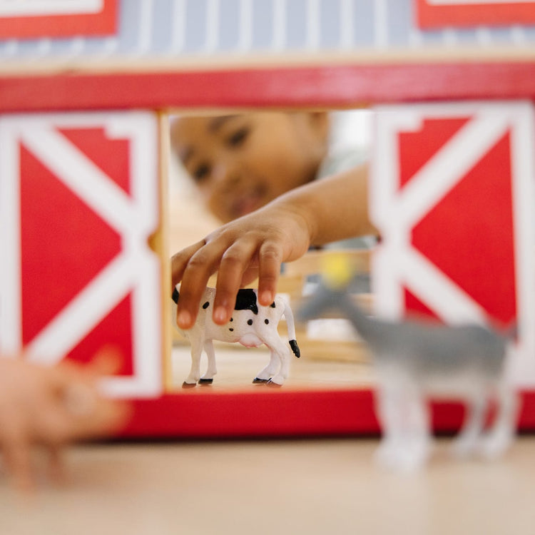A kid playing with the Melissa & Doug Fold and Go Wooden Barn With 7 Animal Play Figures