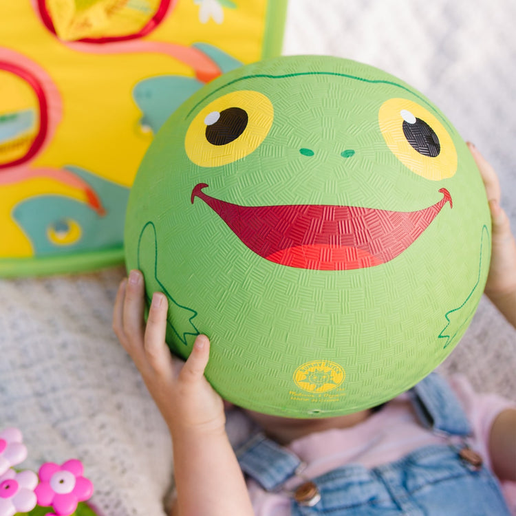 A kid playing with the Melissa & Doug Sunny Patch Froggy Classic Rubber Kickball