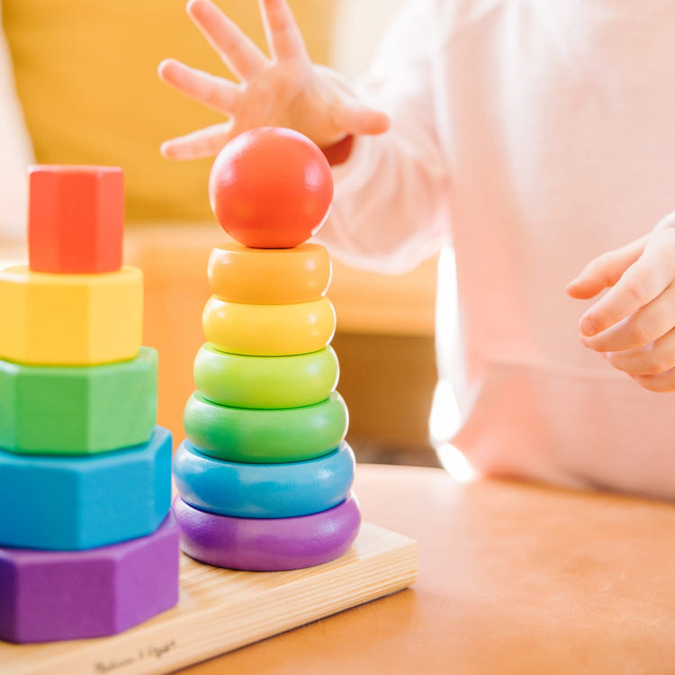 A kid playing with the Melissa & Doug Geometric Stacker - Wooden Educational Toy
