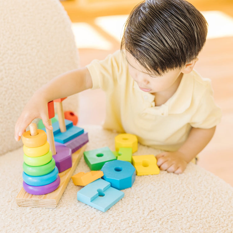 A kid playing with the Melissa & Doug Geometric Stacker - Wooden Educational Toy