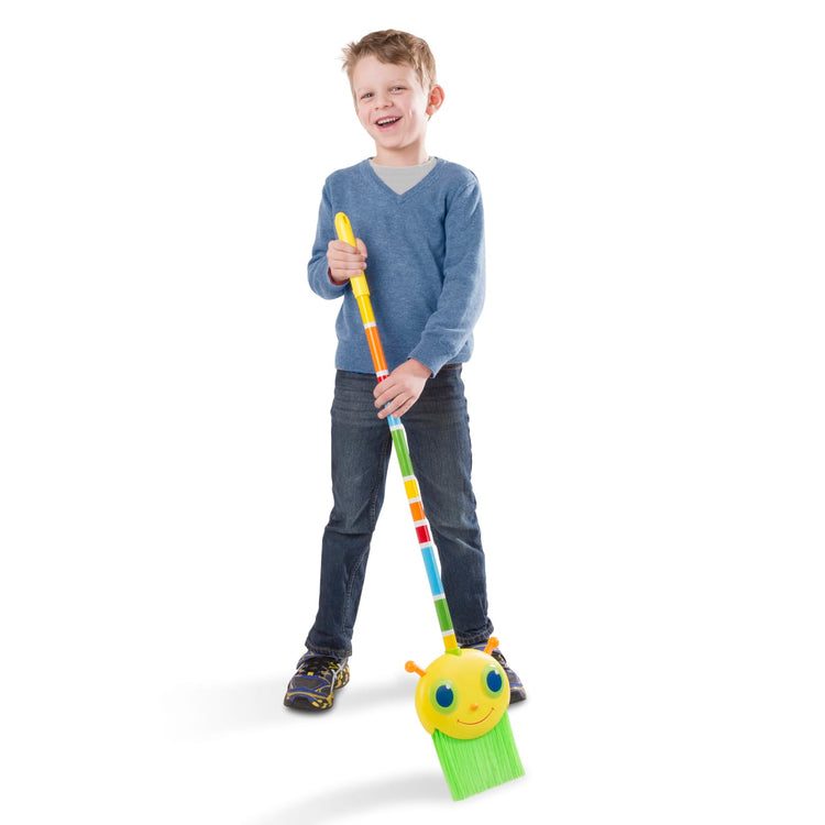 A child on white background with the Melissa & Doug Sunny Patch Giddy Buggy Broom - Pretend Play Toy
