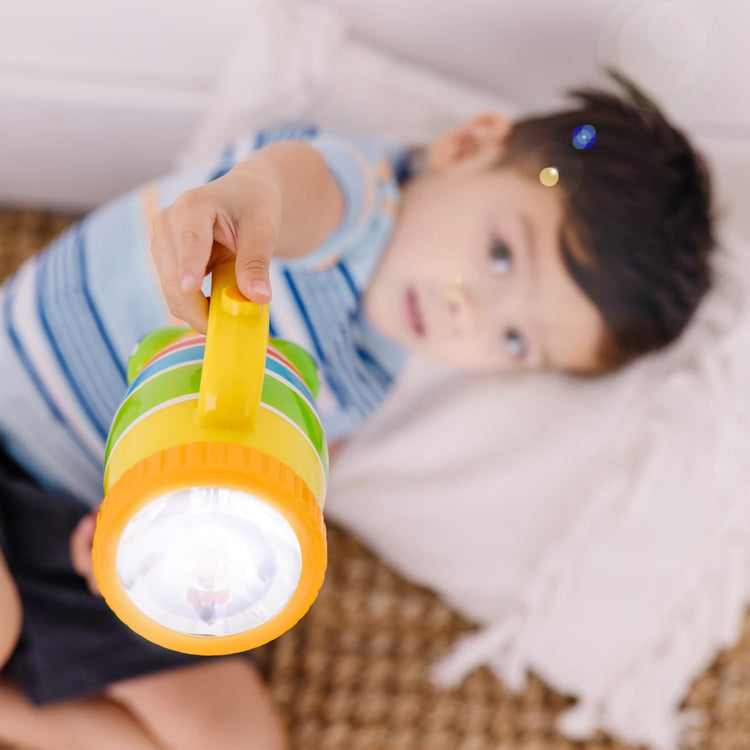 A kid playing with the Melissa & Doug Sunny Patch Giddy Buggy Flashlight With Easy-Grip Handle