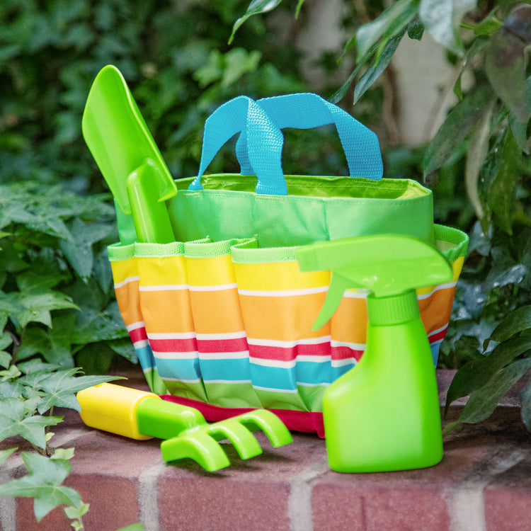 A kid playing with the Melissa & Doug Sunny Patch Giddy Buggy Toy Gardening Tote Set With Tools