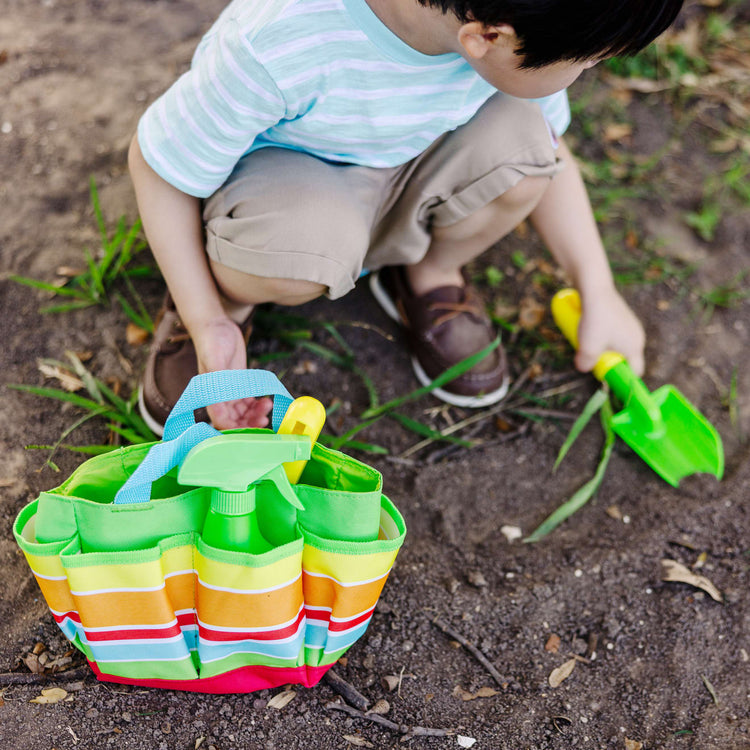 A kid playing with the Melissa & Doug Sunny Patch Giddy Buggy Toy Gardening Tote Set With Tools