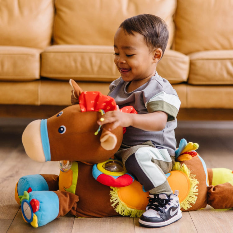A kid playing with the Melissa & Doug Giddy-Up and Play Baby Activity Toy - Multi-Sensory Horse