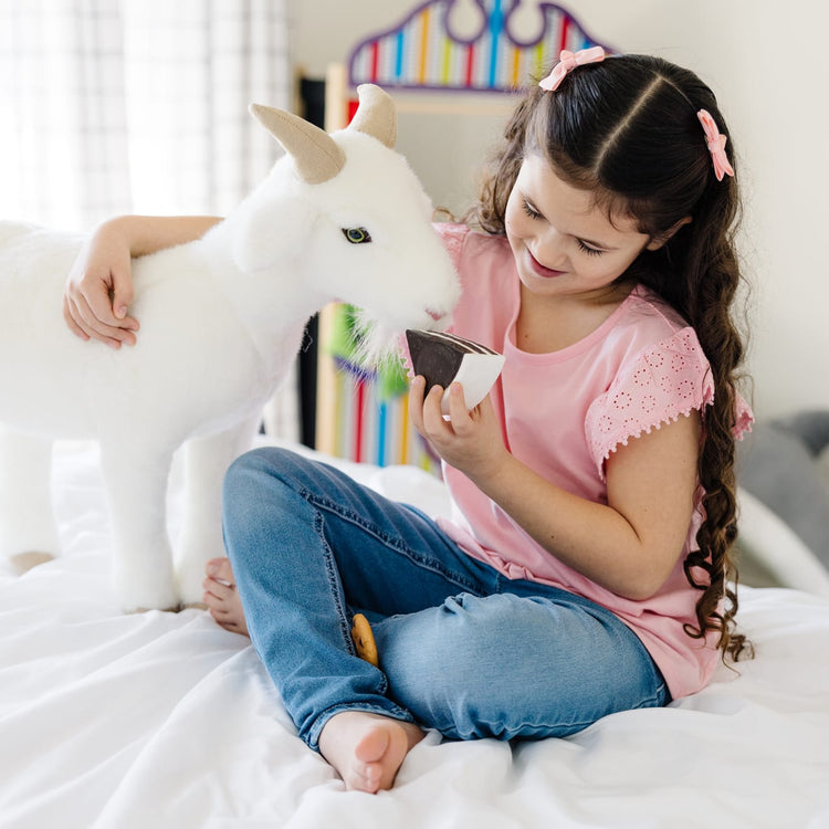 A kid playing with the Melissa & Doug Giant Goat - Lifelike Stuffed Animal (22.5 inches tall)