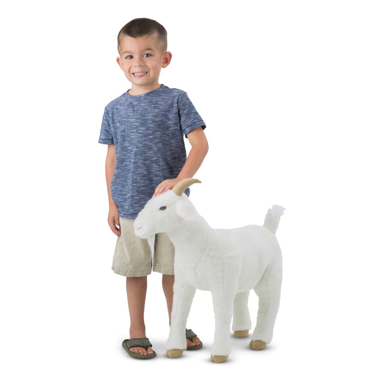 A child on white background with the Melissa & Doug Giant Goat - Lifelike Stuffed Animal (22.5 inches tall)