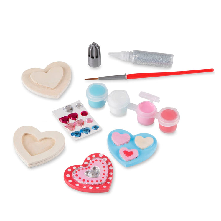 The loose pieces of the Melissa & Doug Created by Me! Wooden Heart Magnets Craft Kit (4 Designs, 4 Paints, Stickers, Glitter Glue)
