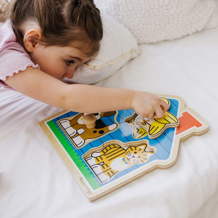 A kid playing with the Melissa & Doug Pets Jumbo Knob Wooden Puzzle