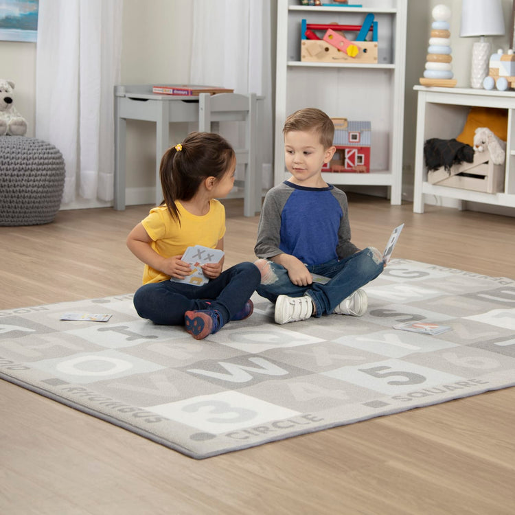 A kid playing with the Melissa & Doug Jumbo ABC-123 Rug Neutral (58 x 79 inches – 36 Game Cards)