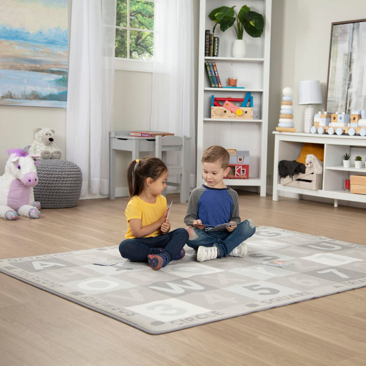 A kid playing with the Melissa & Doug Jumbo ABC-123 Rug Neutral (58 x 79 inches – 36 Game Cards)