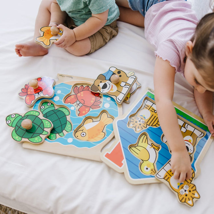 A kid playing with the Melissa & Doug Animals Jumbo Peg Wooden Puzzles 2-Pack - Fish and Pets