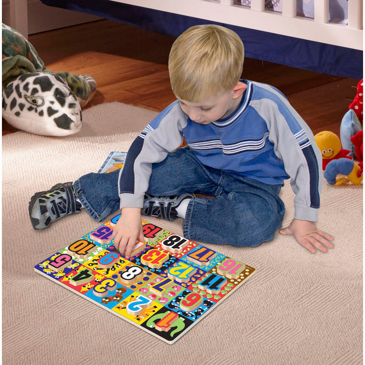 A kid playing with the Melissa & Doug Jumbo Numbers Wooden Chunky Puzzle (20 pcs)