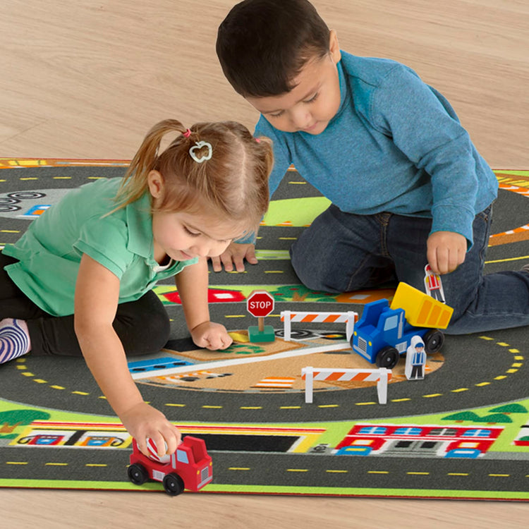 A kid playing with the Melissa & Doug Jumbo Roadway Activity Rug With 4 Wooden Traffic Signs (79 x 58 inches)