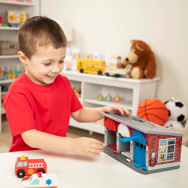 A kid playing with the Melissa & Doug Toy Keys and Cars Wooden Rescue Vehicles and Garage (7 pcs)