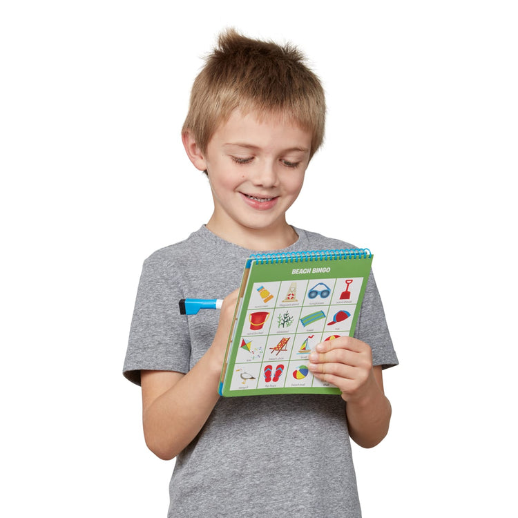 A child on white background with the Melissa & Doug Let’s Explore Seek & Find Bingo Play Set – 2 20-Page Reusable Activity Pads, 2 Dry-Erase Markers
