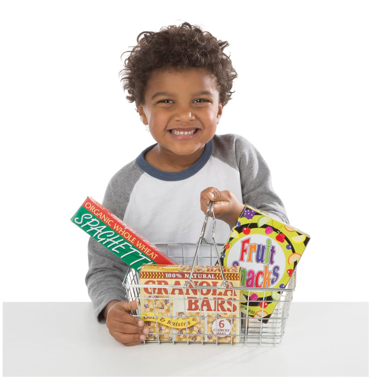 A child on white background with the Melissa & Doug Grocery Basket - Pretend Play Toy With Heavy Gauge Steel Construction