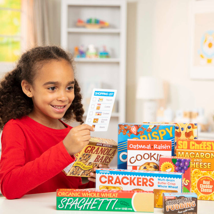 A kid playing with the Melissa & Doug Grocery Boxes for Pretend Kitchens and Shopping (11 pcs)