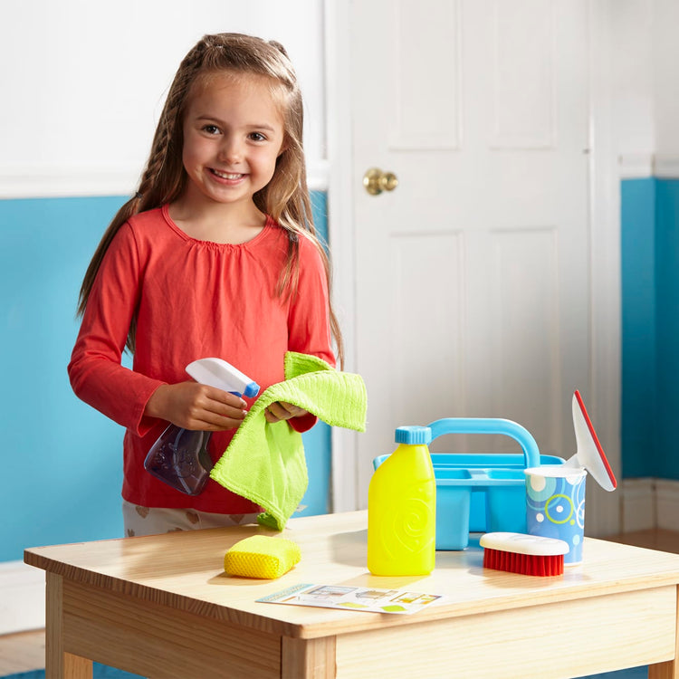 A kid playing with the Melissa & Doug Spray, Squirt & Squeegee Play Set - Pretend Play Cleaning Set