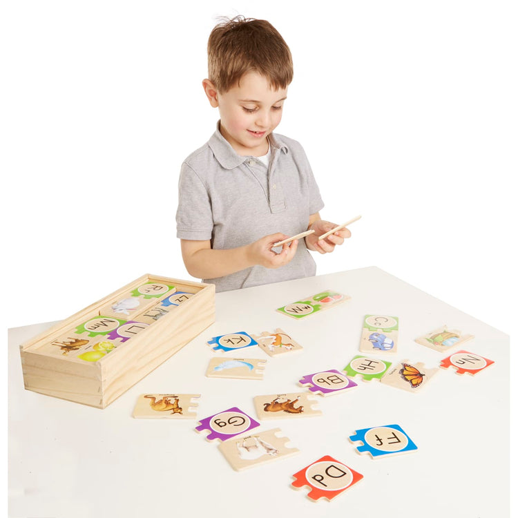 A child on white background with the Melissa & Doug Wooden Self-Correcting Alphabet Letter Puzzles With Storage Box (52 pcs)