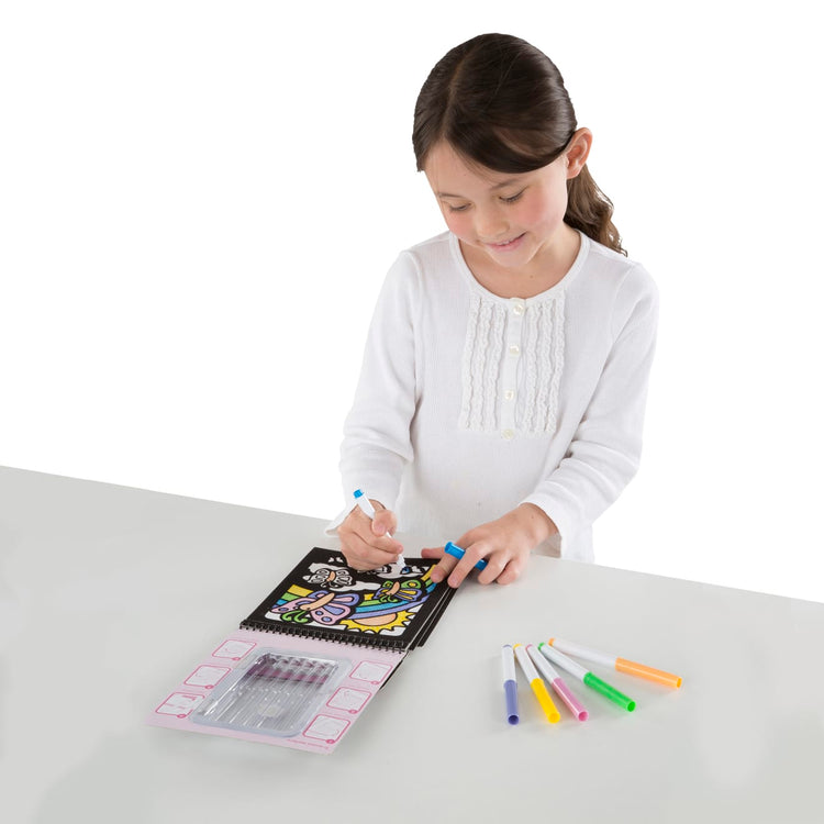 A child on white background with the Melissa & Doug On the Go Magic Velvet Pattern-Reveal Scenes Activity Kit - 6 Coloring Boards, 6 Markers