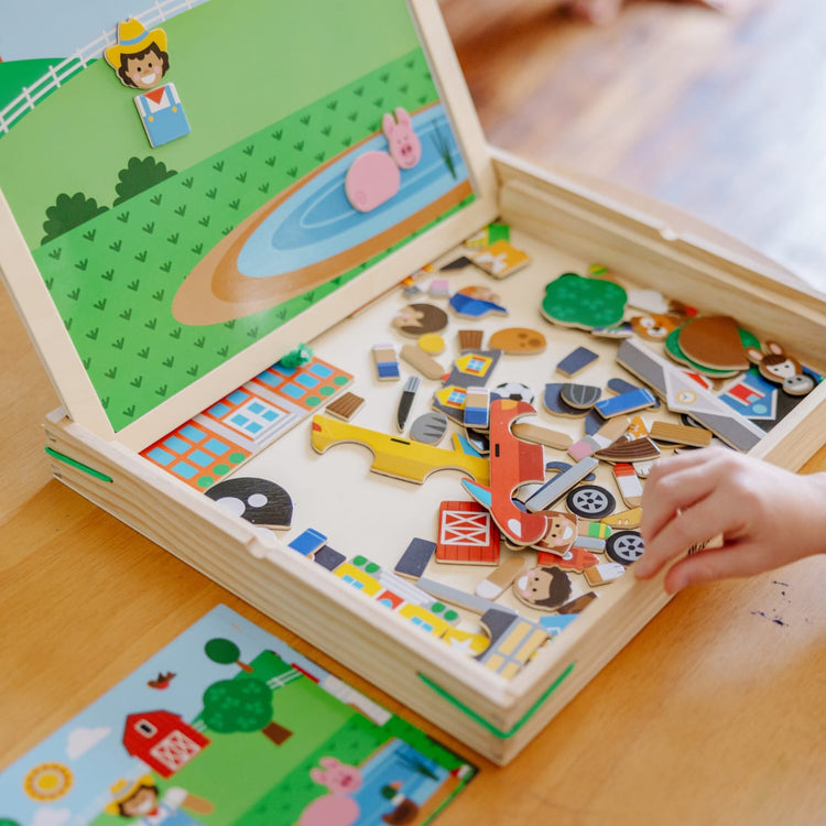 A kid playing with the Melissa & Doug Wooden Magnetic Matching Picture Game With 119 Magnets and Scene Cards