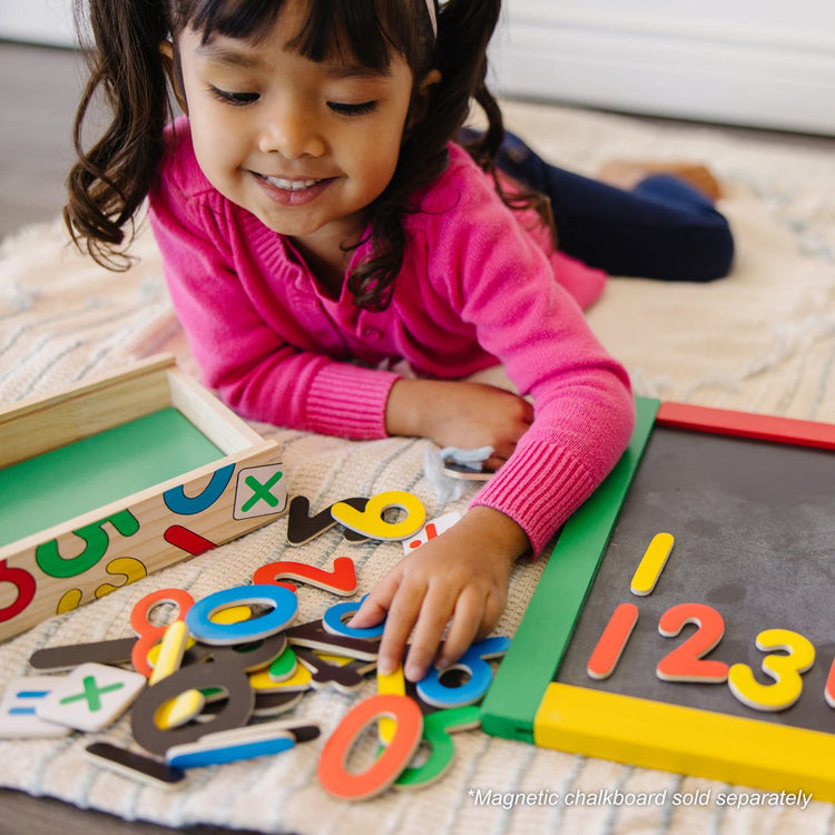 A kid playing with the Melissa & Doug 37 Wooden Number Magnets in a Box