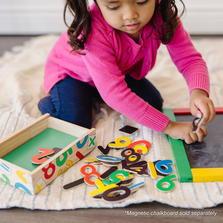 A kid playing with the Melissa & Doug 37 Wooden Number Magnets in a Box