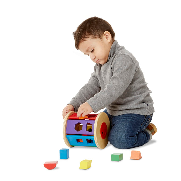 A child on white background with the Melissa & Doug Match and Roll Shape Sorter - Classic Wooden Toy