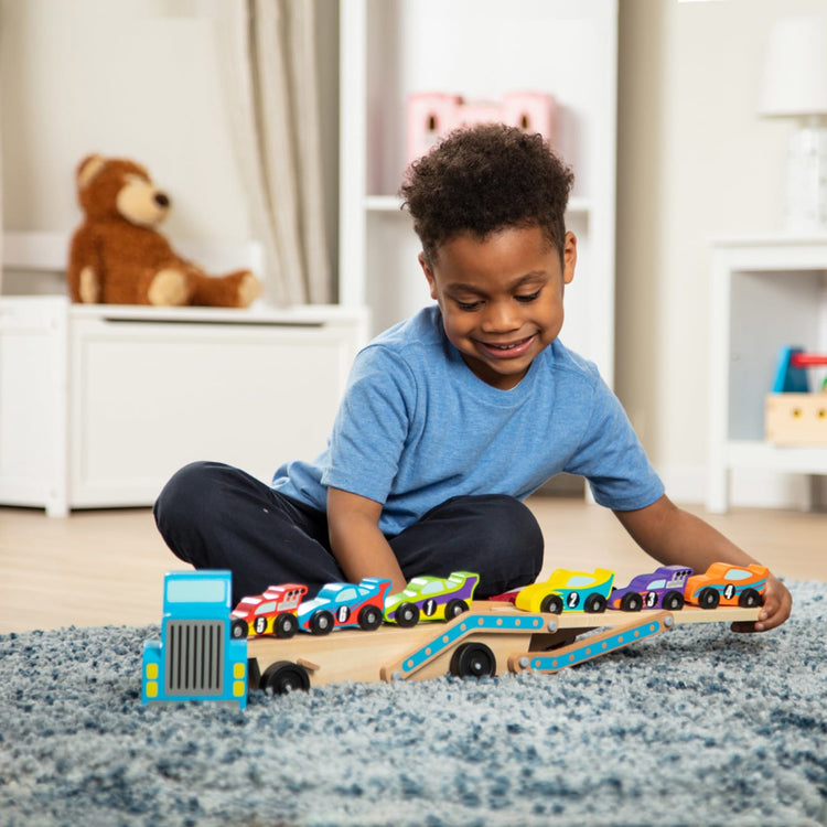 A kid playing with the Melissa & Doug Mega Race-Car Carrier - Wooden Tractor and Trailer With 6 Unique Race Cars