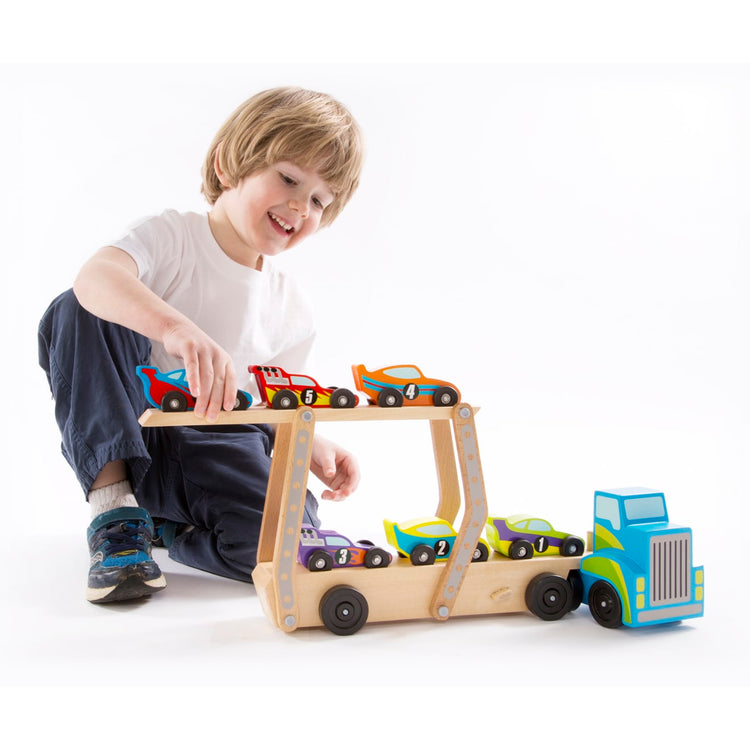 A child on white background with the Melissa & Doug Mega Race-Car Carrier - Wooden Tractor and Trailer With 6 Unique Race Cars