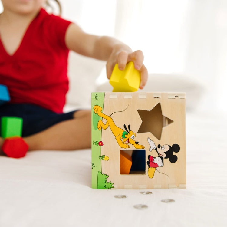 A kid playing with the Mickey Mouse & Friends Wooden Shape Sorting Cube