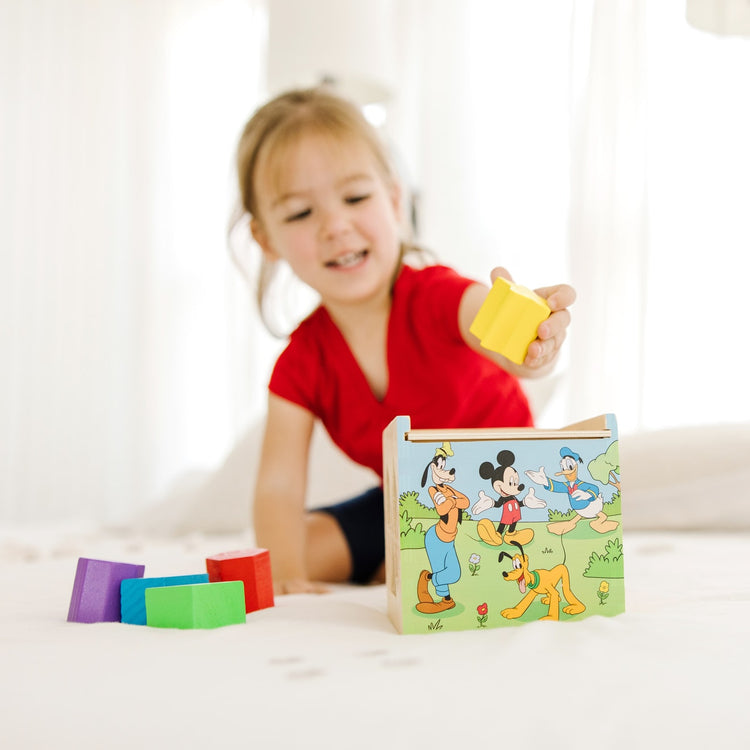 A kid playing with the Mickey Mouse & Friends Wooden Shape Sorting Cube