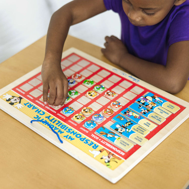 A kid playing with the Melissa & Doug Disney Mickey Mouse Clubhouse My Magnetic Responsibility Chart