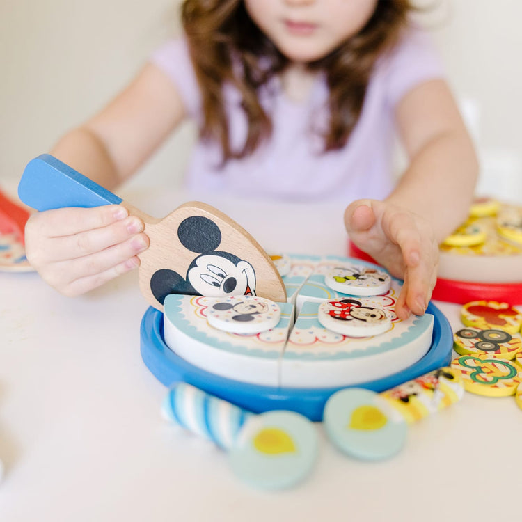 A kid playing with the Melissa & Doug Mickey Mouse Wooden Pizza and Birthday Cake Set (32 pcs) - Play Food
