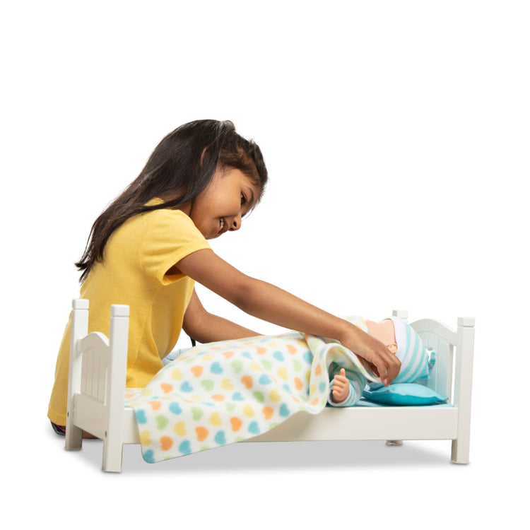 A child on white background with the Melissa & Doug Mine to Love Wooden Play Bed for Dolls, Stuffed Animals - White (8.7”H x 9.1”W x 20.7”L Assembled)