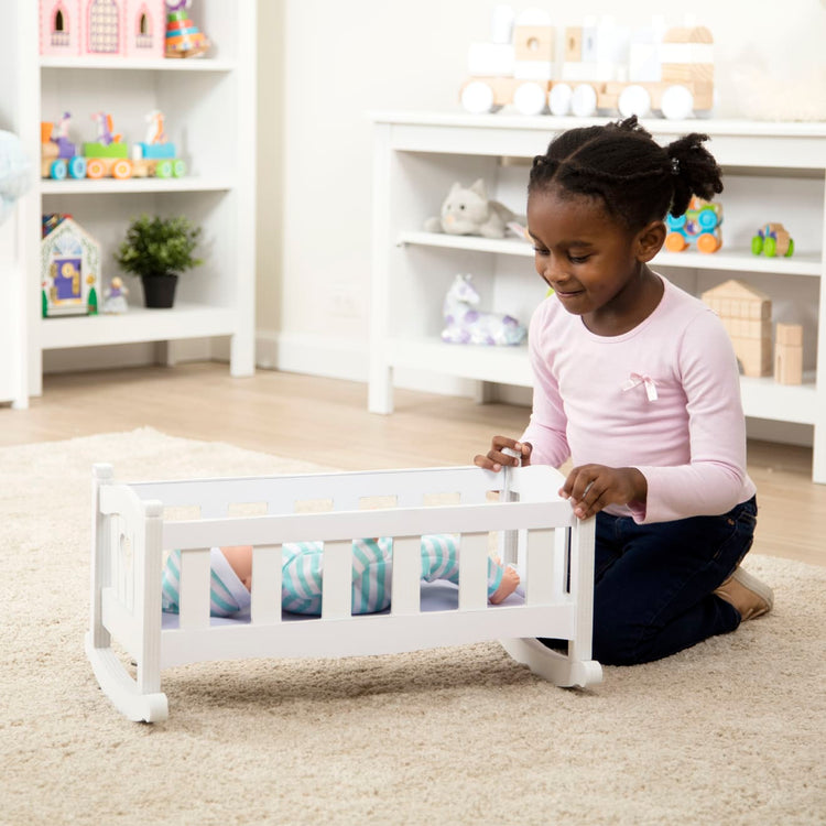 A kid playing with the Melissa & Doug Mine to Love Wooden Play Cradle for Dolls, Stuffed Animals - White