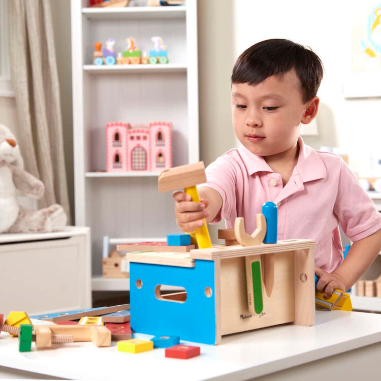 A kid playing with the Melissa & Doug Hammer and Saw Tool Bench - Wooden Building Set (32 pcs)